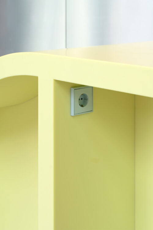 Detail of solid surface table with high and low side bright yellow composite with grey socket by dutch invertuals studio