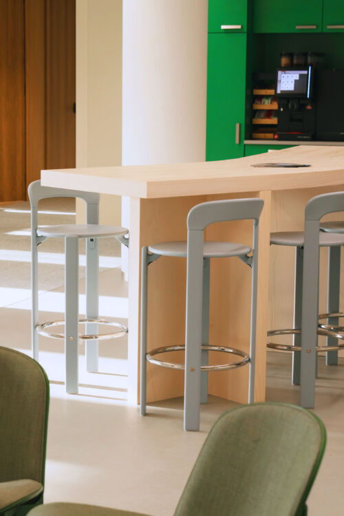 Wooden high table with blue hay rey chairs in coworking pantry space in Breda design by dutch invertuals studio